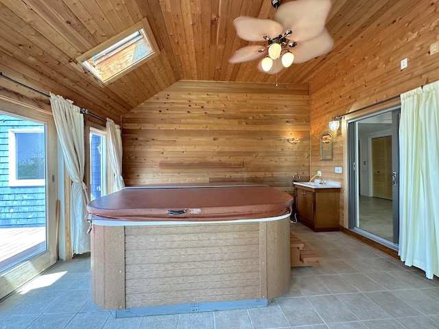 bathroom featuring wood ceiling, wooden walls, ceiling fan, lofted ceiling with skylight, and vanity