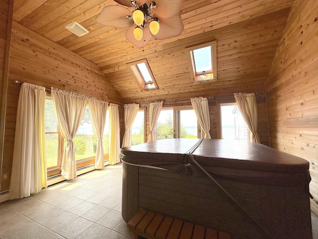 interior space with light tile patterned floors, a skylight, wood ceiling, wooden walls, and ceiling fan