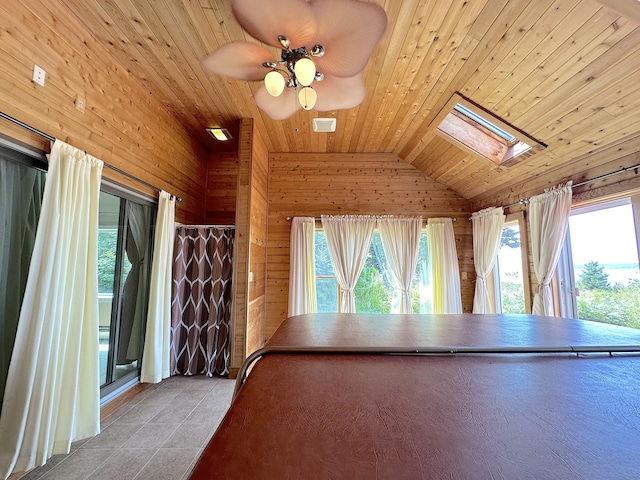 interior space featuring ceiling fan, lofted ceiling with skylight, wood walls, light tile patterned flooring, and wooden ceiling