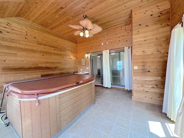 interior space with wood ceiling, a hot tub, wooden walls, ceiling fan, and vaulted ceiling