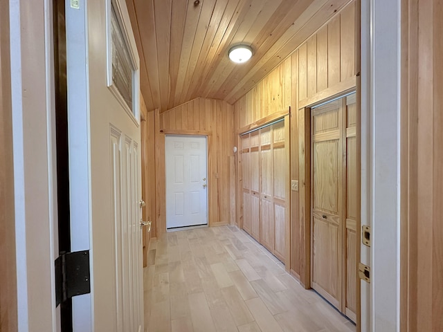 hallway with vaulted ceiling, light wood-type flooring, wood ceiling, and wooden walls