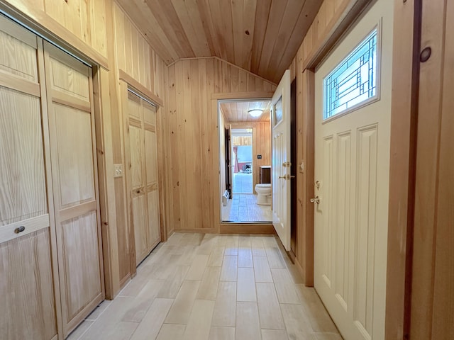 doorway to outside featuring wooden ceiling, vaulted ceiling, and wooden walls