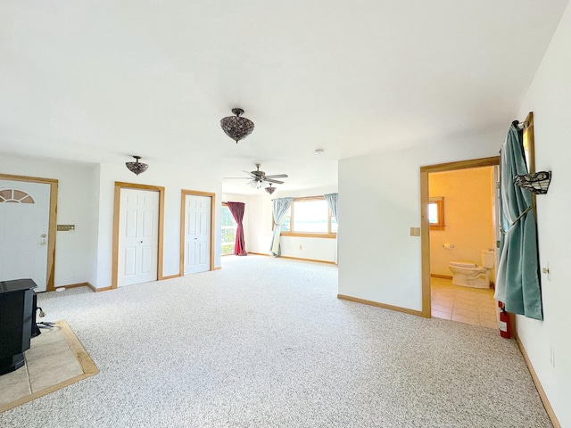 interior space featuring ceiling fan, a wood stove, and carpet flooring