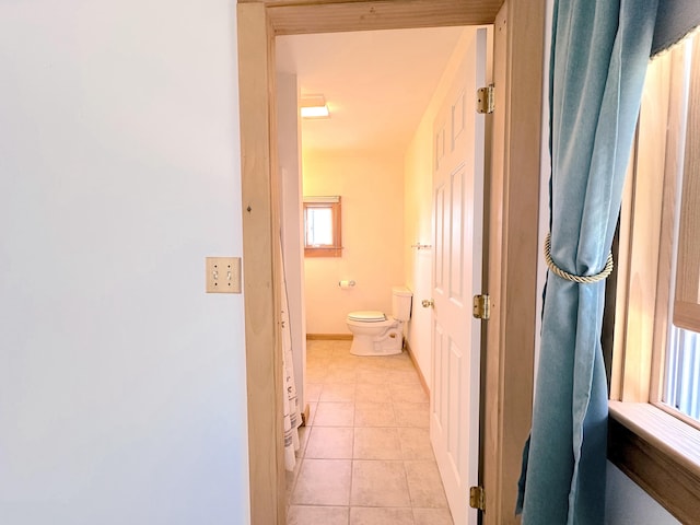 bathroom featuring toilet, tile patterned flooring, and a wealth of natural light