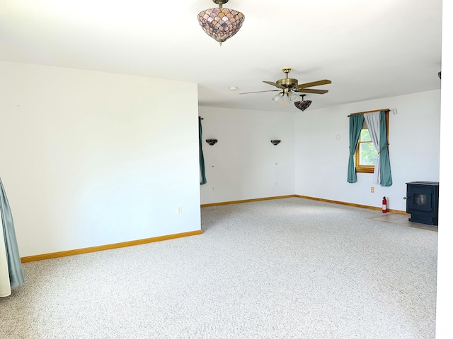 unfurnished room featuring ceiling fan and a wood stove