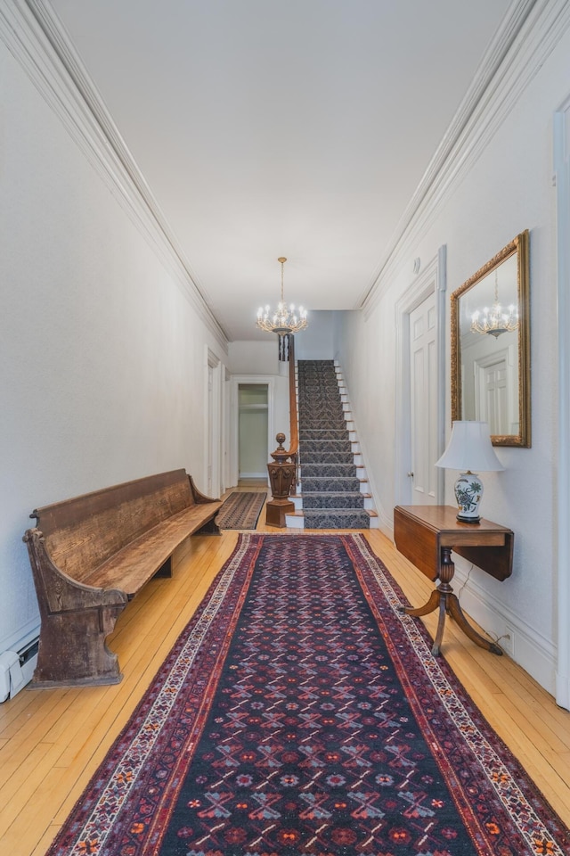 hall featuring wood-type flooring, an inviting chandelier, and ornamental molding