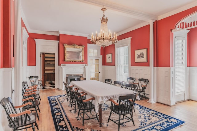 dining area with ornamental molding, a chandelier, light hardwood / wood-style flooring, and decorative columns