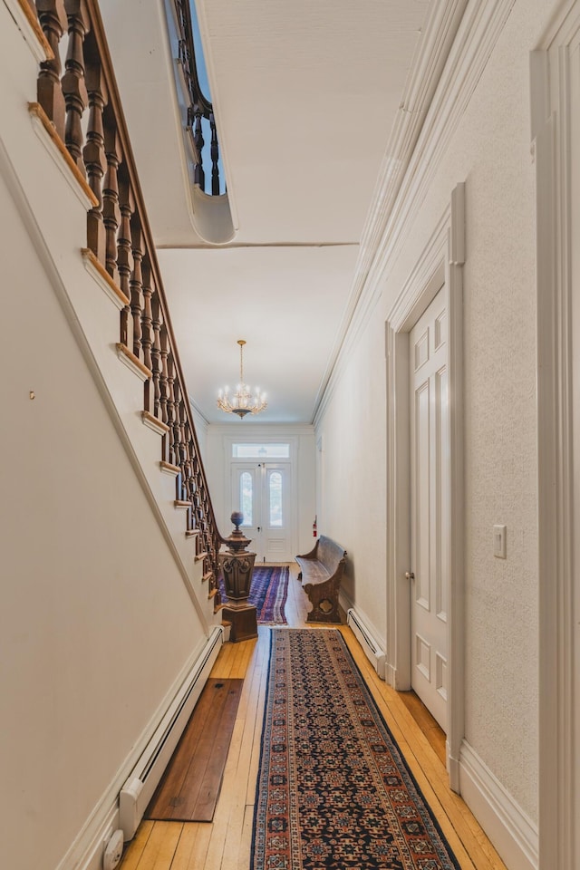 interior space with a baseboard heating unit, light hardwood / wood-style flooring, ornamental molding, and french doors