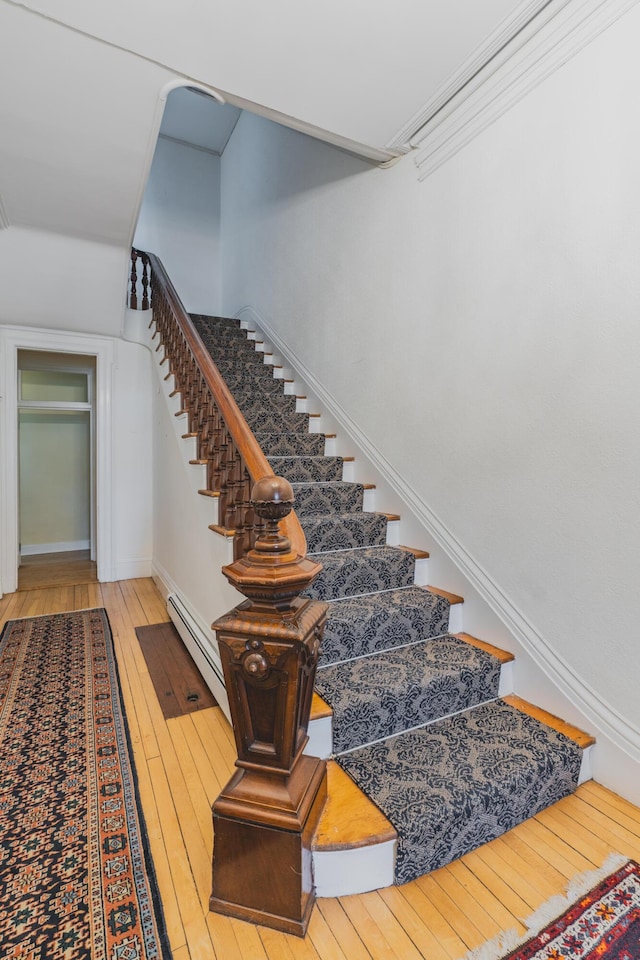 stairs featuring hardwood / wood-style floors and ornamental molding