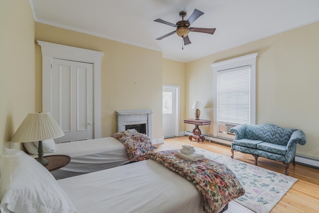 bedroom featuring ceiling fan, crown molding, wood-type flooring, and a baseboard radiator