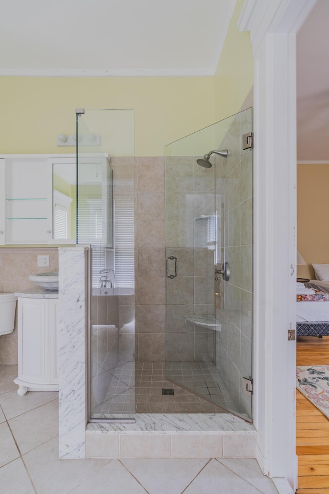 bathroom with an enclosed shower, tile patterned flooring, and ornamental molding