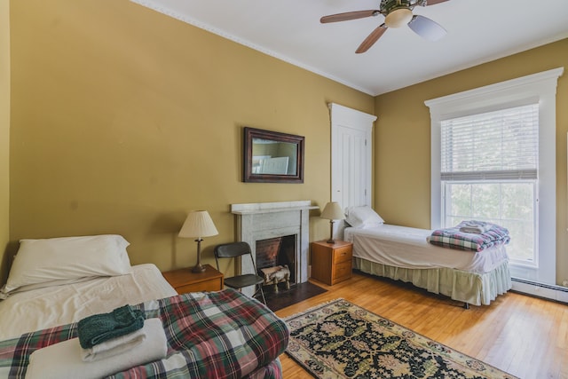 bedroom with ceiling fan, light hardwood / wood-style floors, and a high end fireplace