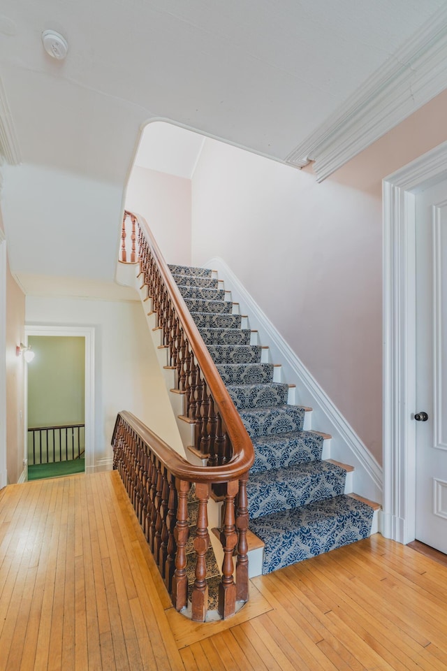 staircase with crown molding and hardwood / wood-style flooring