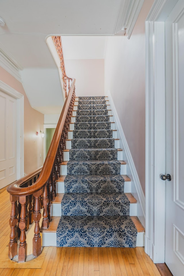 stairs featuring hardwood / wood-style floors and crown molding