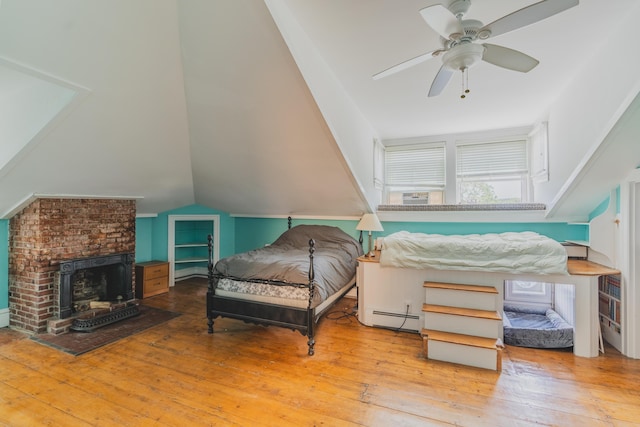 bedroom featuring ceiling fan, light hardwood / wood-style flooring, vaulted ceiling, and a baseboard heating unit