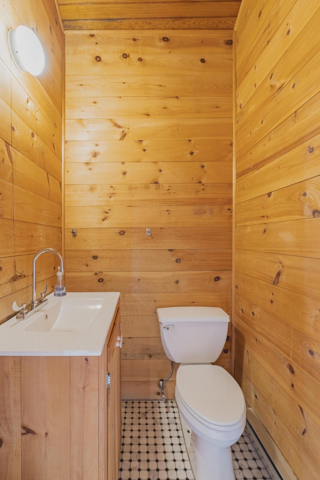 bathroom featuring toilet, vanity, and wooden walls