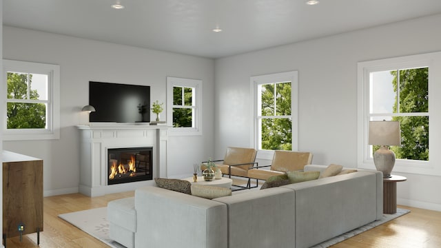 living area featuring recessed lighting, light wood-style flooring, baseboards, and a glass covered fireplace