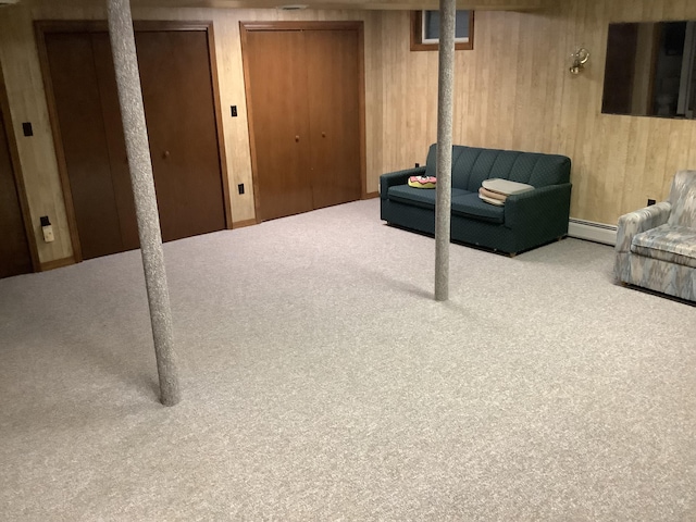 basement with baseboard heating, carpet flooring, and wooden walls