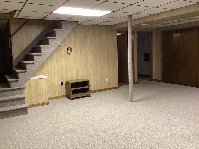 basement featuring light carpet and wood walls