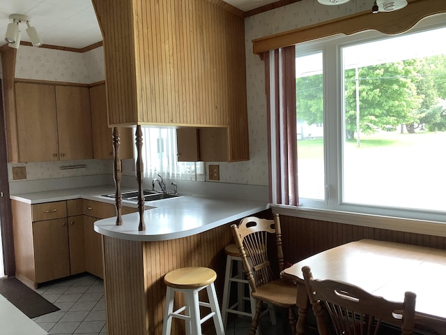 kitchen with sink, a kitchen breakfast bar, kitchen peninsula, and light tile patterned flooring