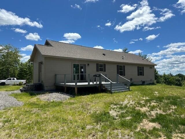 rear view of property with a wooden deck and a lawn