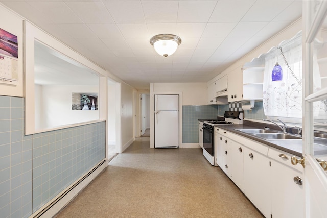 kitchen featuring under cabinet range hood, a sink, baseboard heating, freestanding refrigerator, and gas stove