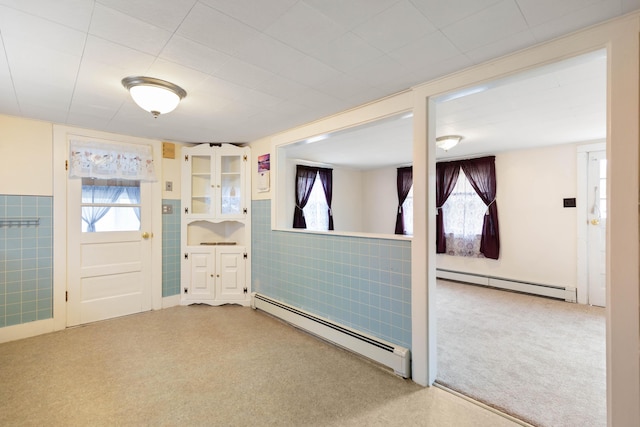 entrance foyer featuring a baseboard radiator, tile walls, and a wealth of natural light