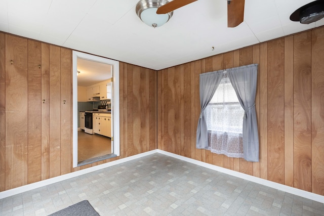 unfurnished room featuring wood walls, baseboards, and tile patterned floors