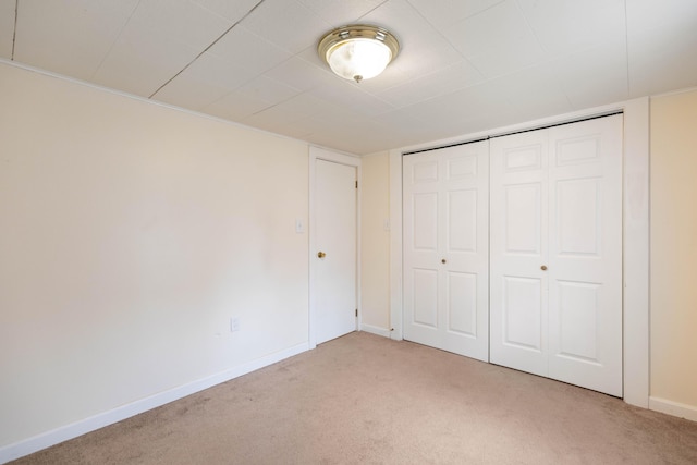 unfurnished bedroom featuring baseboards, a closet, and light colored carpet
