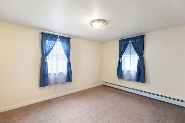 empty room with a baseboard heating unit, a wealth of natural light, carpet floors, and baseboards