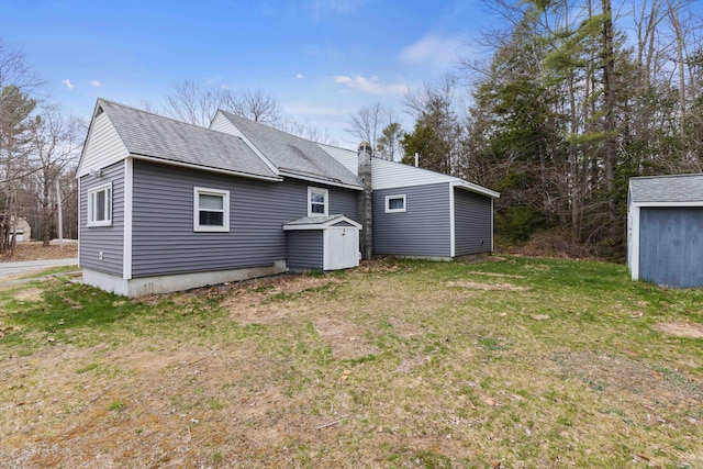 rear view of property with an outbuilding, a shed, and a lawn