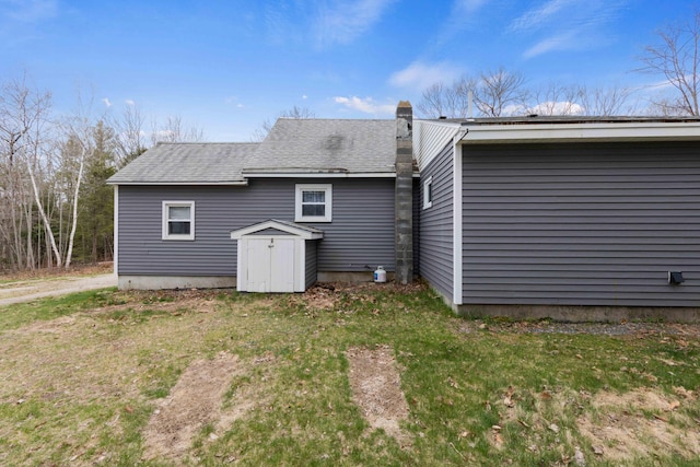 rear view of house featuring roof with shingles and a chimney