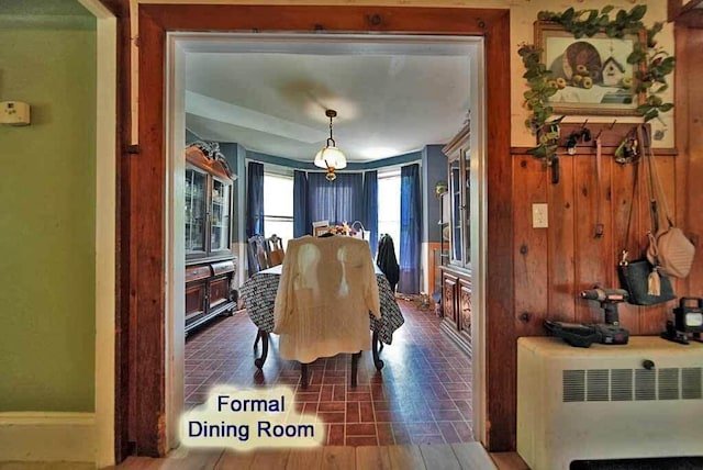 dining area featuring wood walls and radiator heating unit