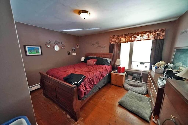 bedroom featuring wood-type flooring and a baseboard heating unit