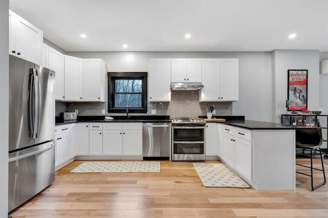 kitchen with stainless steel appliances, white cabinets, and a kitchen breakfast bar