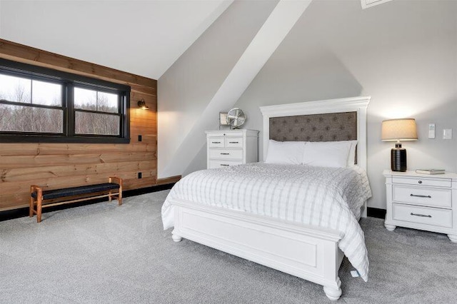 bedroom with wood walls, vaulted ceiling, and carpet flooring