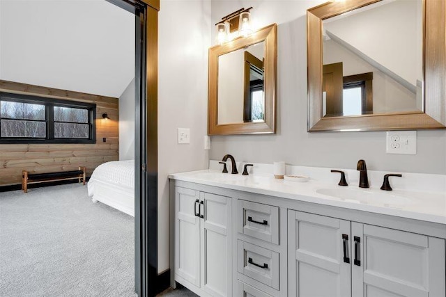 ensuite bathroom with double vanity, wood walls, ensuite bath, and a sink