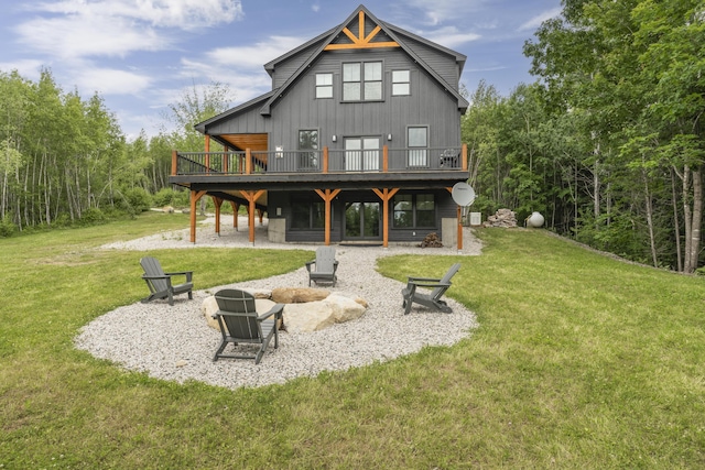 back of house featuring an outdoor fire pit, a lawn, a deck, and a patio