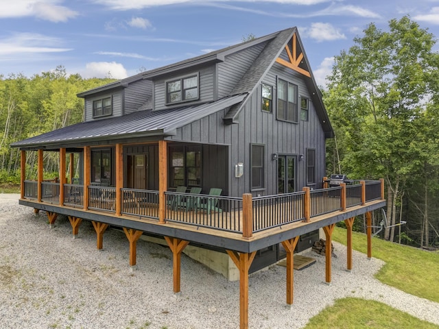 back of house with a shingled roof, metal roof, and a wooden deck