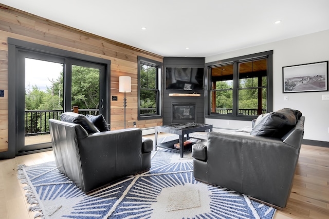 living room with recessed lighting, light wood-style flooring, a baseboard heating unit, a large fireplace, and wood walls