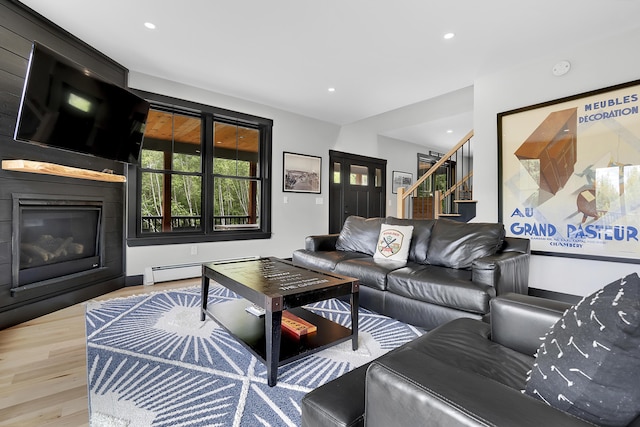 living area featuring recessed lighting, a baseboard heating unit, a fireplace, wood finished floors, and stairway