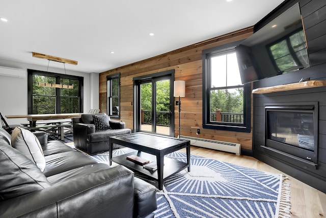 living area featuring a baseboard radiator, an AC wall unit, a glass covered fireplace, and light wood finished floors