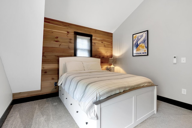 bedroom featuring lofted ceiling, wood walls, baseboards, and light colored carpet