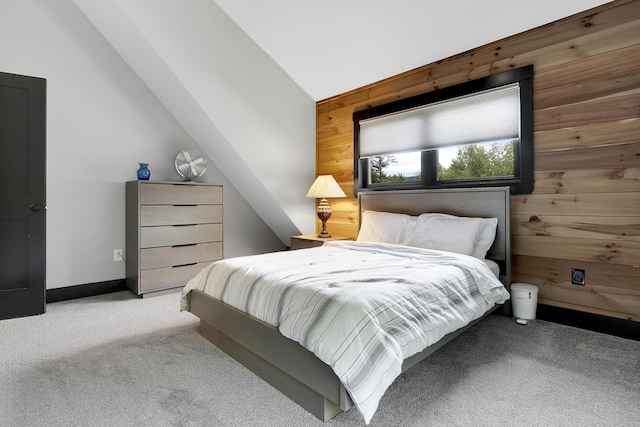 bedroom featuring lofted ceiling, light colored carpet, wooden walls, and baseboards