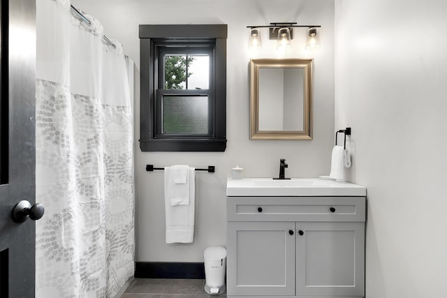 full bath with curtained shower, tile patterned flooring, baseboards, and vanity