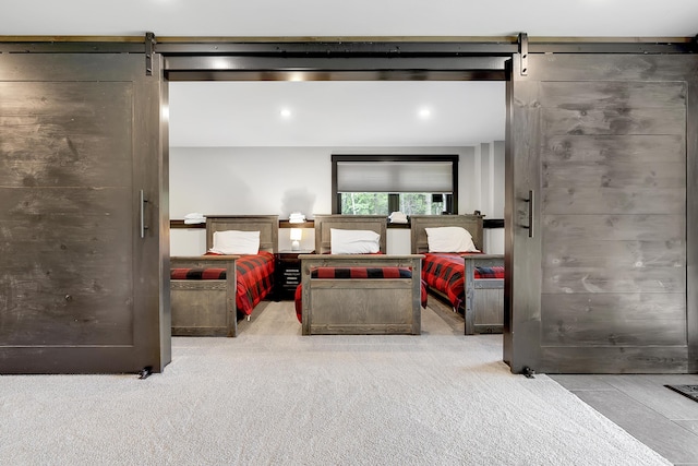 bedroom with a barn door and light colored carpet