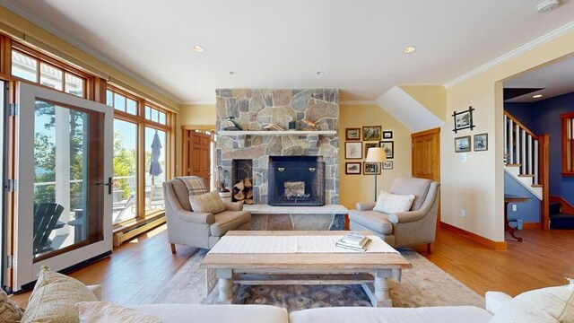 living room with a fireplace, light wood-type flooring, baseboard heating, and ornamental molding