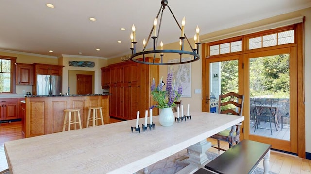 dining space with crown molding, french doors, a notable chandelier, and light wood-type flooring