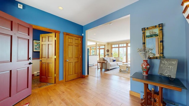 corridor with light hardwood / wood-style floors and a baseboard heating unit