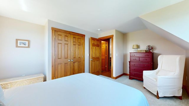 bedroom with lofted ceiling, light carpet, and a closet